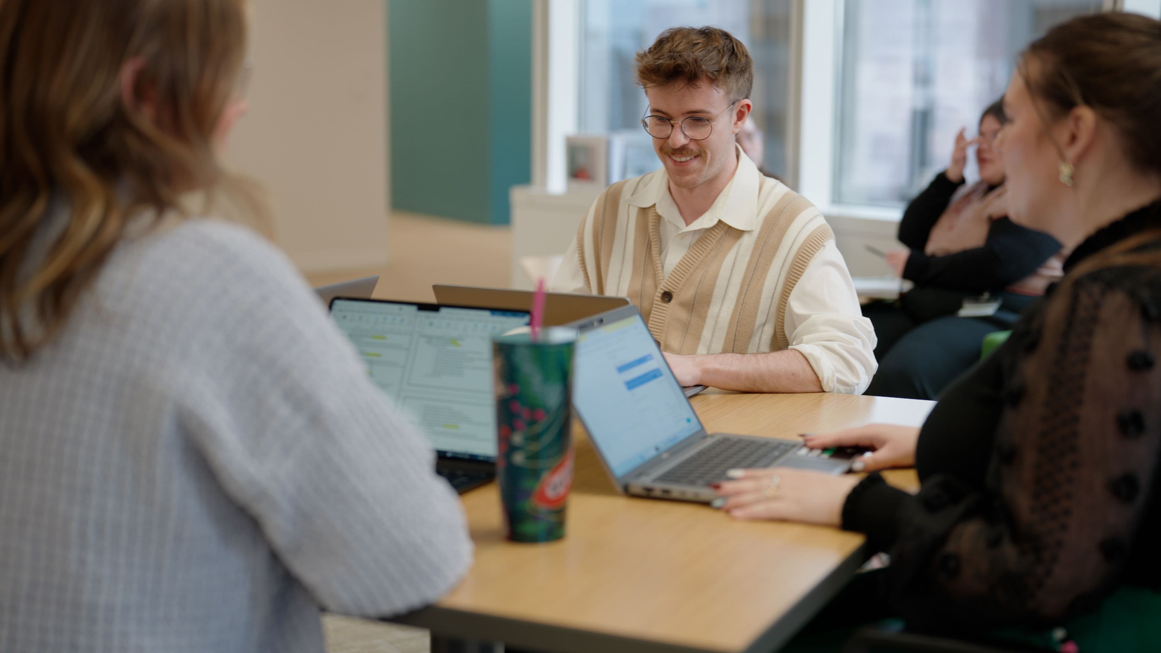 People at a square table with laptops working together