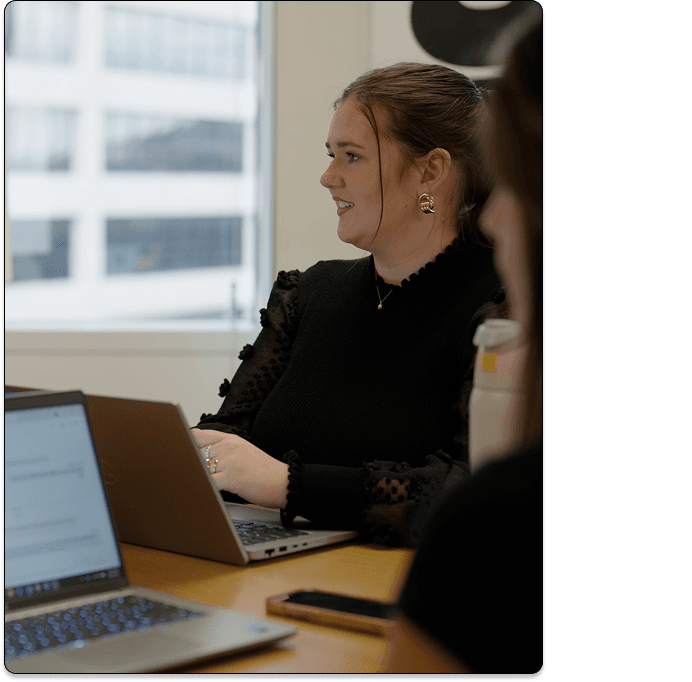Two women working with laptops in front in a meeting.
